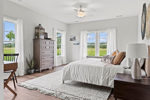 bedroom featuring hardwood / wood-style floors, ceiling fan, and multiple windows