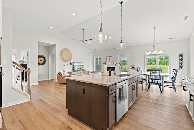 kitchen featuring dishwasher, a kitchen island with sink, sink, light stone countertops, and dark brown cabinets