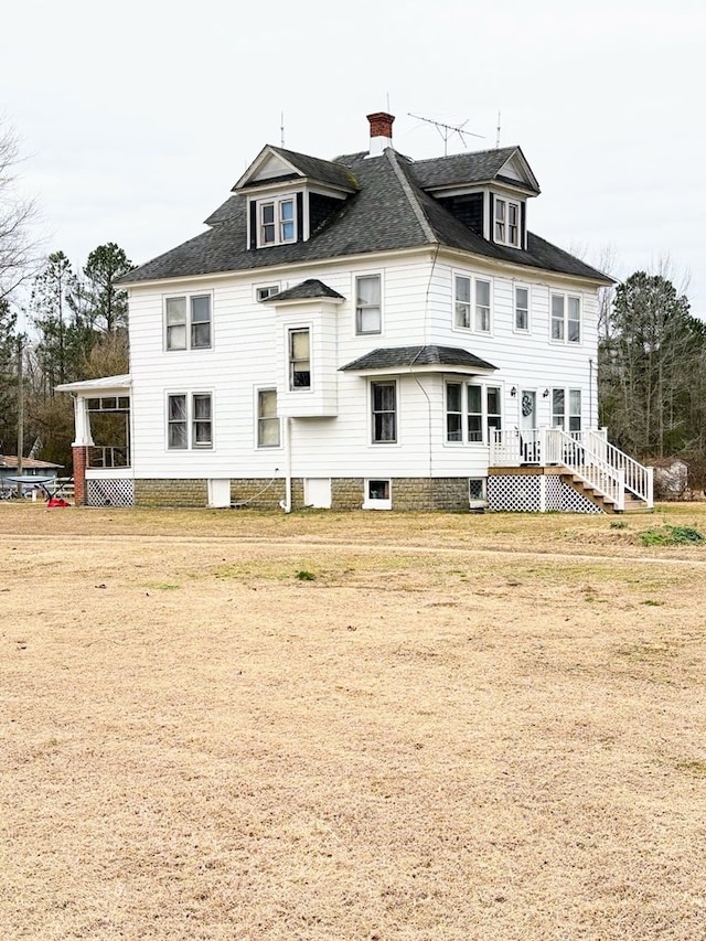 back of house featuring roof with shingles and a chimney