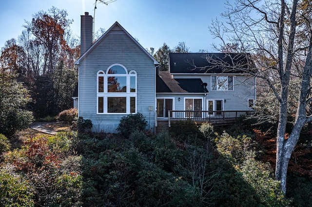 back of property with a chimney and a wooden deck