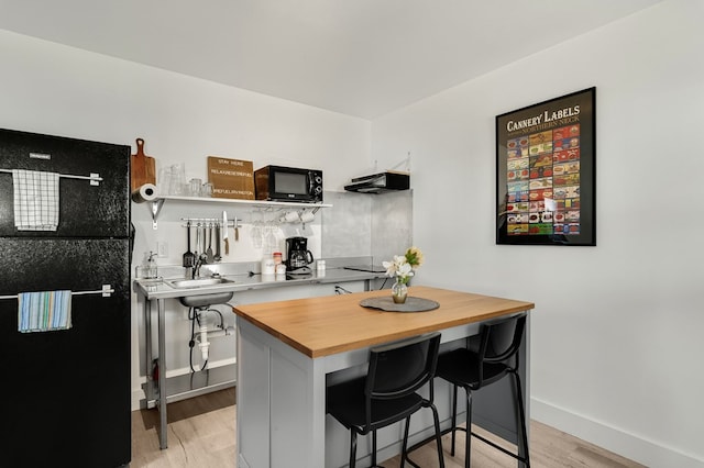 kitchen featuring a breakfast bar area, white cabinetry, ventilation hood, light hardwood / wood-style flooring, and kitchen peninsula