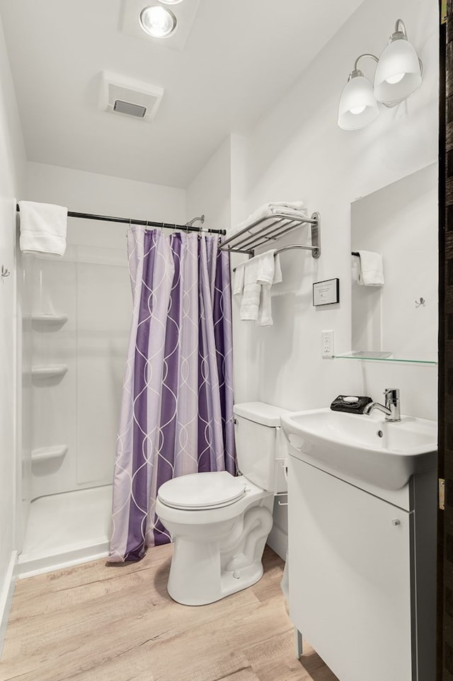 bathroom featuring hardwood / wood-style flooring, vanity, curtained shower, and toilet