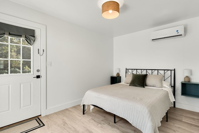 bedroom featuring light hardwood / wood-style flooring and a wall mounted AC