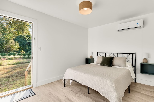 bedroom with a wall mounted AC and light hardwood / wood-style flooring