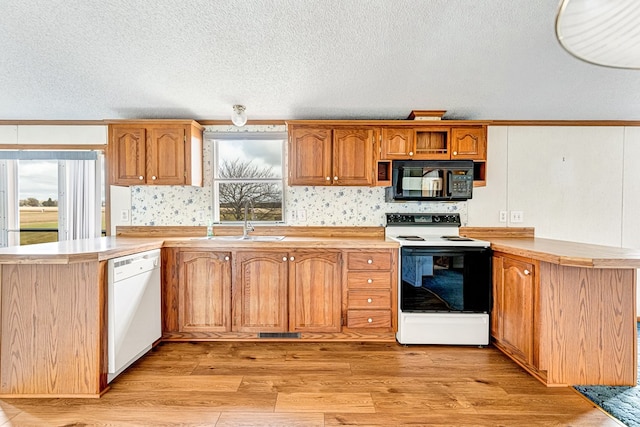 kitchen featuring white appliances, kitchen peninsula, and a wealth of natural light