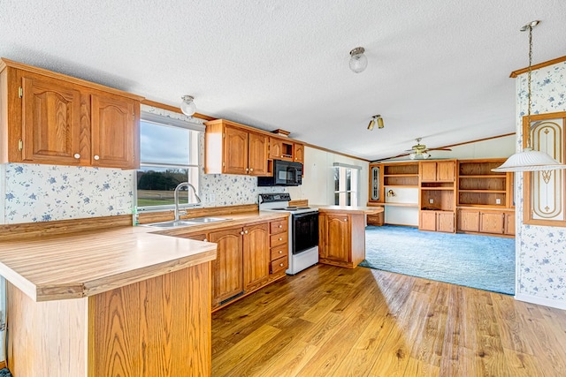 kitchen featuring electric range, sink, kitchen peninsula, decorative light fixtures, and light wood-type flooring