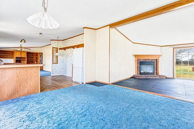 unfurnished living room featuring ceiling fan, ornamental molding, and a fireplace