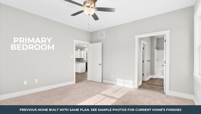 unfurnished bedroom featuring ceiling fan, light colored carpet, and ensuite bath