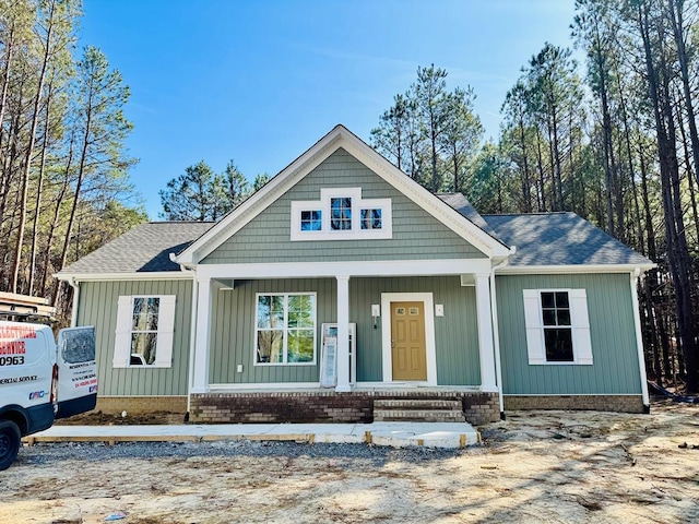 view of front of home with board and batten siding, covered porch, and roof with shingles