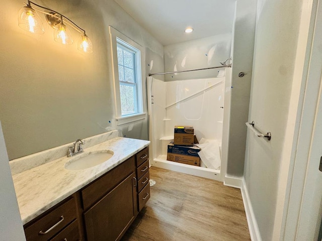 bathroom with baseboards, vanity, wood finished floors, and a shower stall