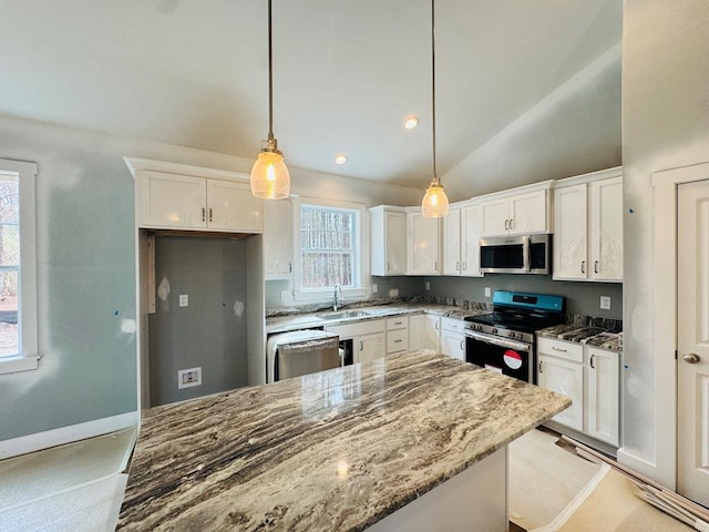 kitchen with stone counters, white cabinetry, stainless steel appliances, and a sink