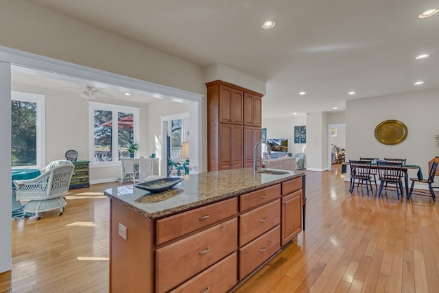 kitchen featuring light wood-style flooring, a sink, light stone countertops, and recessed lighting