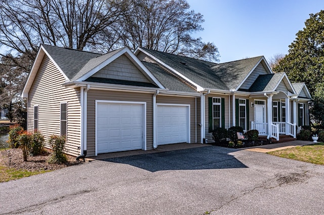 ranch-style house with roof with shingles, an attached garage, and aphalt driveway