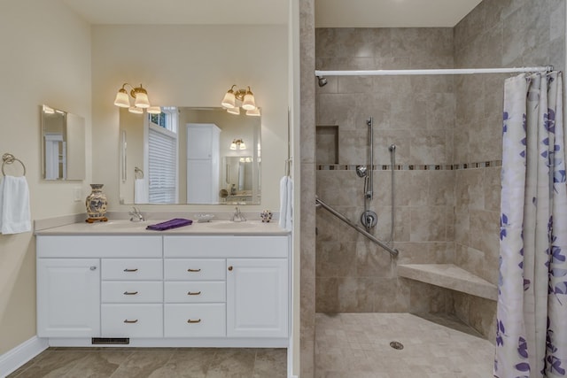full bathroom featuring a sink, double vanity, visible vents, and a tile shower