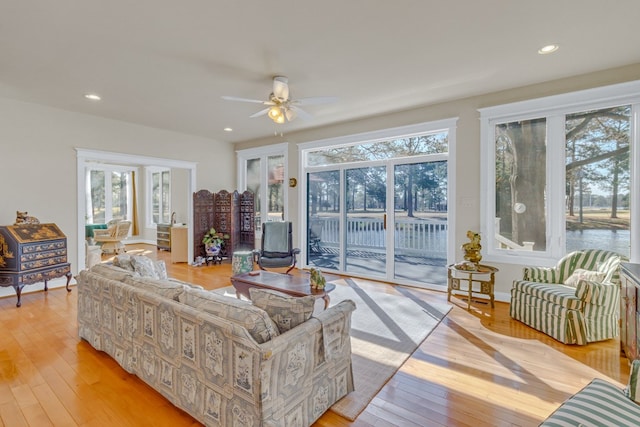 living room with a ceiling fan, light wood-style floors, and a healthy amount of sunlight