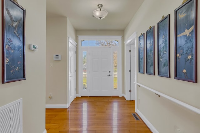 foyer with baseboards, visible vents, and light wood-style floors