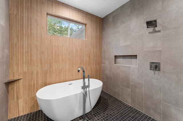 bathroom featuring tile patterned floors, a tub, and tile walls