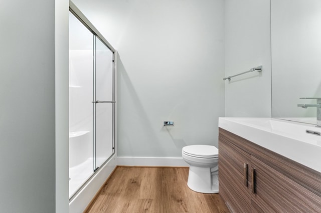 bathroom with an enclosed shower, vanity, toilet, and wood-type flooring