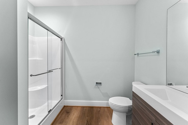 bathroom with a shower with door, vanity, wood-type flooring, and toilet