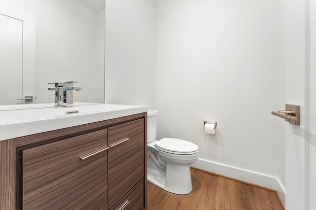 bathroom with wood-type flooring, vanity, and toilet