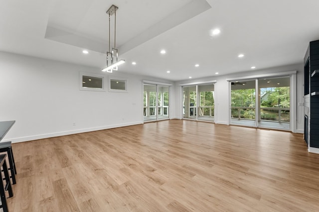 unfurnished living room featuring light hardwood / wood-style floors and a raised ceiling