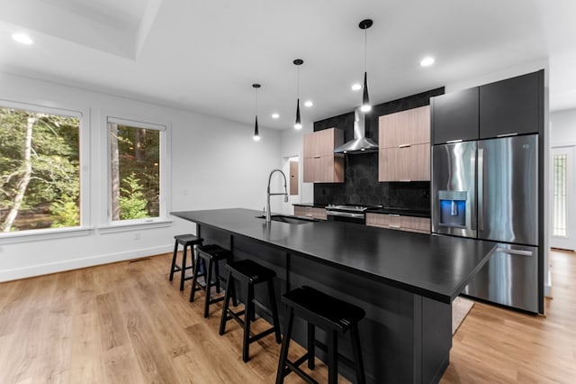 kitchen featuring appliances with stainless steel finishes, a kitchen island with sink, pendant lighting, and sink