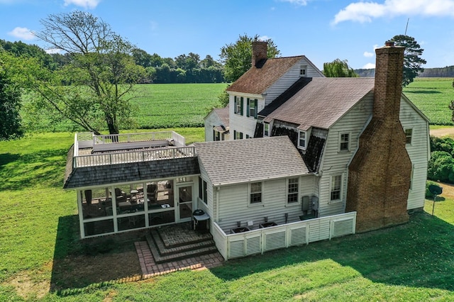 rear view of house featuring a sunroom, a yard, and a rural view