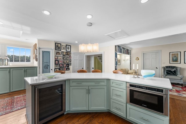 kitchen featuring ornamental molding, beverage cooler, dark wood-type flooring, decorative light fixtures, and green cabinetry