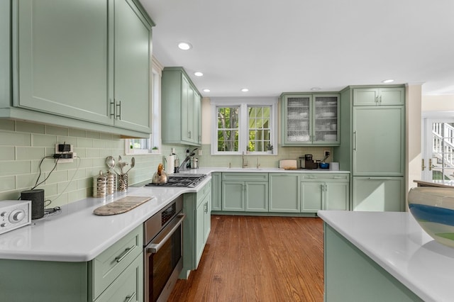 kitchen featuring backsplash, light hardwood / wood-style flooring, stainless steel appliances, and green cabinetry