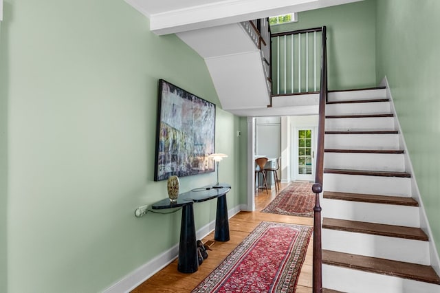 staircase featuring wood-type flooring and vaulted ceiling