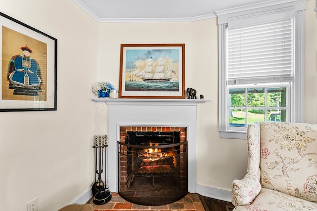 living area with hardwood / wood-style flooring, a brick fireplace, and crown molding