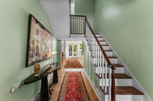 stairs with hardwood / wood-style flooring, a towering ceiling, and french doors