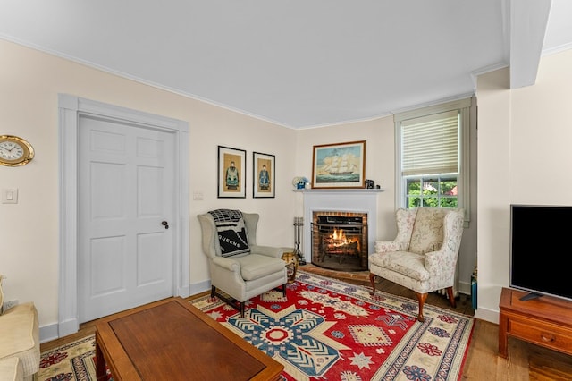 living area with hardwood / wood-style flooring, a brick fireplace, and crown molding