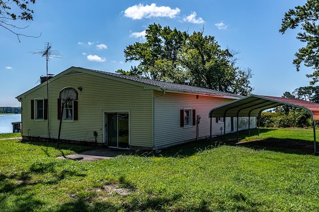 back of house with a carport, a water view, and a yard