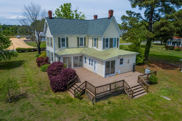 back of house featuring a sunroom, a chimney, a yard, and a deck