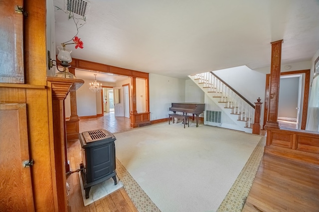 living area with visible vents, a wood stove, wood finished floors, and stairway