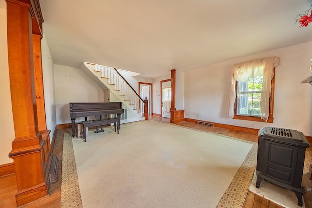 interior space featuring stairway, visible vents, baseboards, and a wood stove