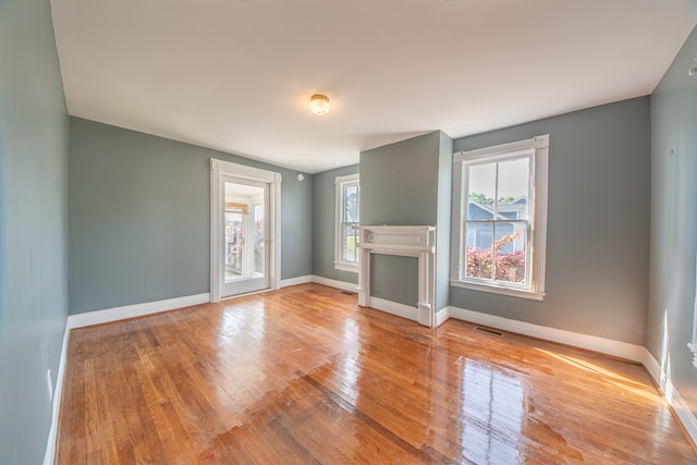 unfurnished living room with a fireplace, baseboards, wood-type flooring, and visible vents