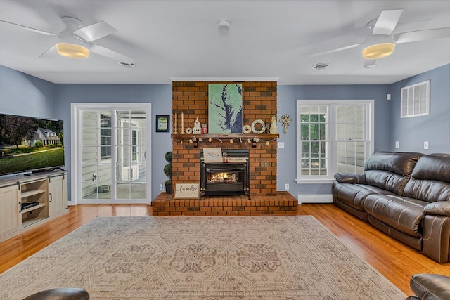 889 Taylors Creek Rd, Weems, VA 22576 - living room featuring ceiling fan, wood finished floors, a baseboard radiator, and a fireplace