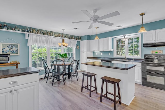 889 Taylors Creek Rd, Weems, VA 22576 - kitchen with double oven range, under cabinet range hood, dark countertops, and white cabinetry