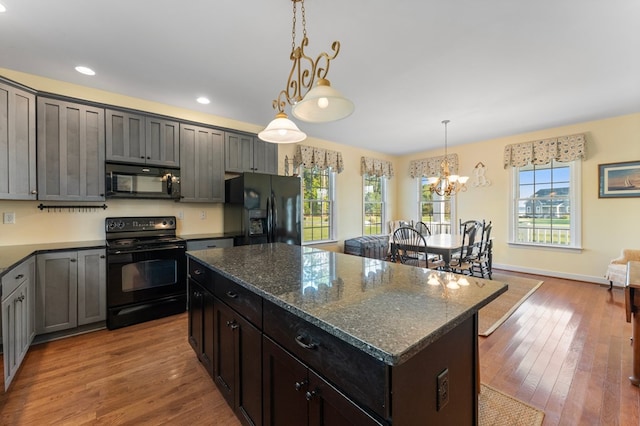 480 Rockingham Rd, Dunnsville, VA 22454 - kitchen with a chandelier, a healthy amount of sunlight, black appliances, and wood finished floors