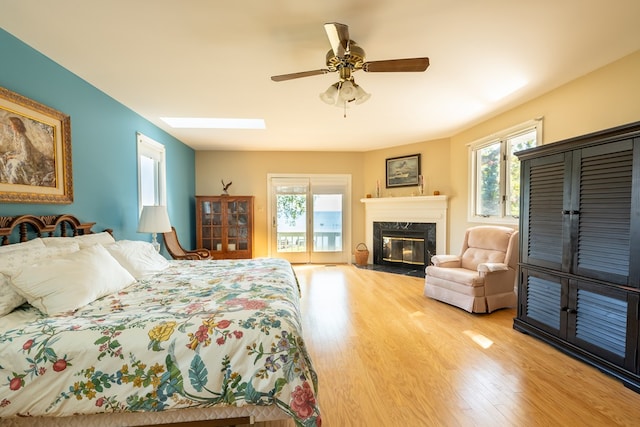 bedroom featuring ceiling fan, access to exterior, wood-type flooring, and multiple windows