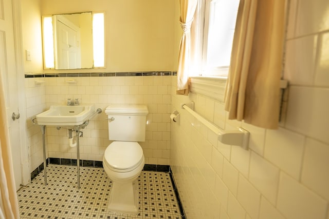 bathroom with tile patterned flooring, toilet, tile walls, and sink