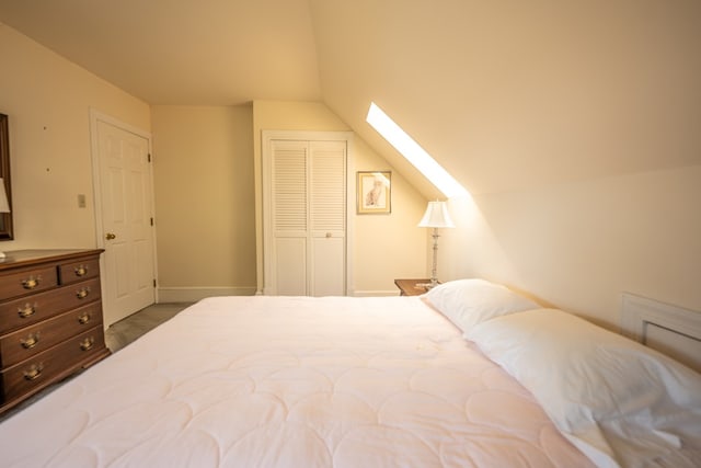 carpeted bedroom with lofted ceiling with skylight and a closet