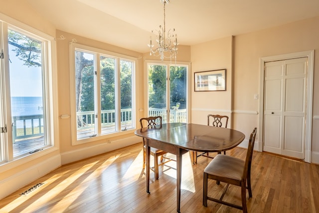 dining space with light hardwood / wood-style floors and a chandelier