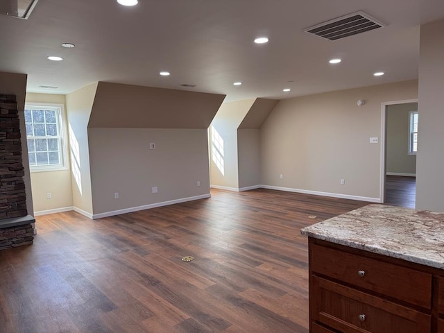 additional living space with dark wood-type flooring, a healthy amount of sunlight, and vaulted ceiling