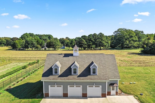 view of front facade with a garage, a rural view, and a front yard