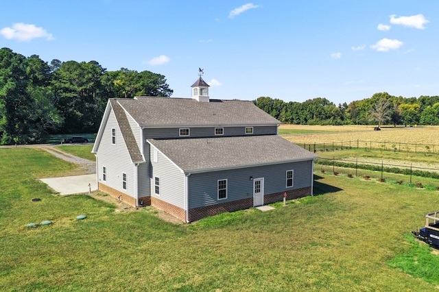 back of house with a rural view and a lawn