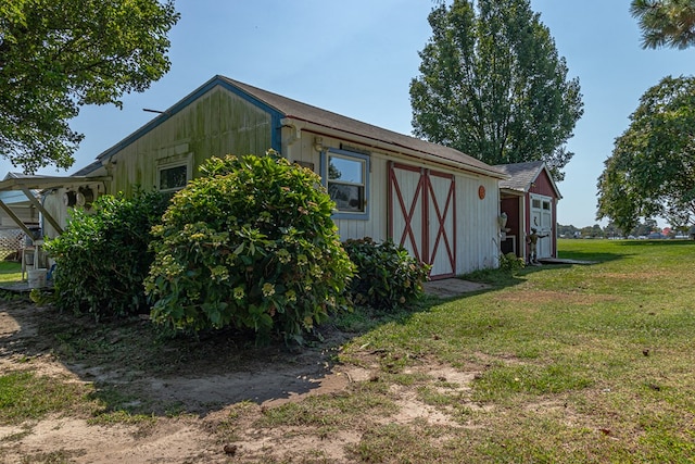 view of side of home with a lawn and an outdoor structure