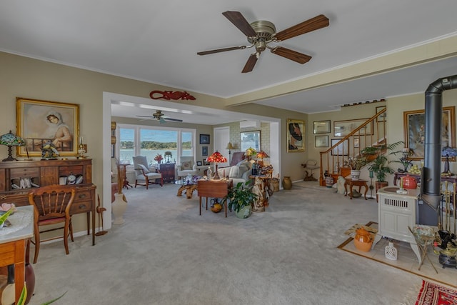 dining space featuring ceiling fan, light colored carpet, a wood stove, and ornamental molding